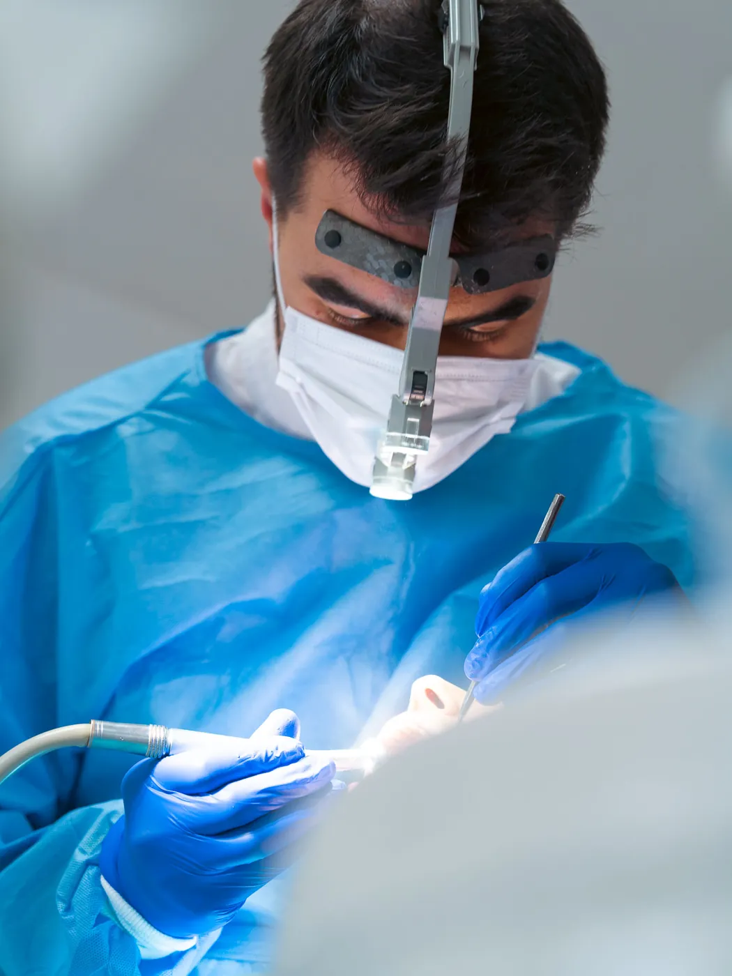 Dent Aydınlıkevler kliniğinde koruyucu önlük ve büyüteç kullanan hekim hasta üzerinde çalışırken
