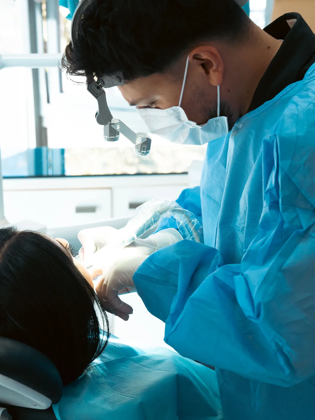 Dent Aydınlıkevler kliniğinde cerrahi önlük giymiş hekimimiz hastasını muayene ederken